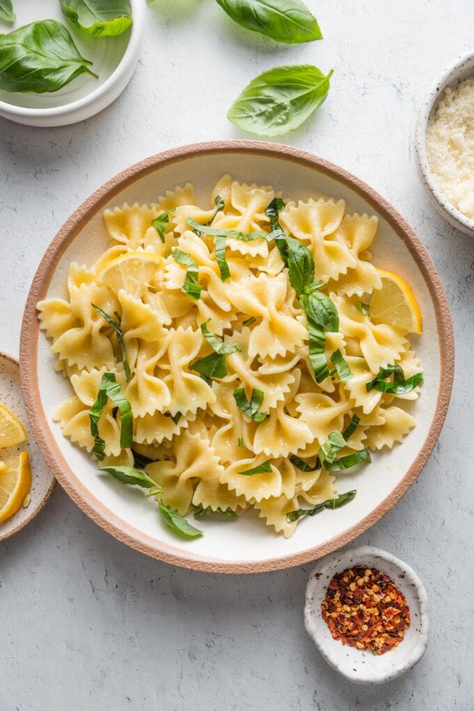 Bowl of bowtie pasta with a light olive oil sauce and fresh basil chiffonade.
