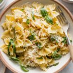 Shallow bowl full of a simple basil pasta dish with a hint of lemon juice and Parmesan cheese.