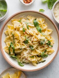 Serving of lemon basil pasta with generously dusted fresh Parmesan cheese and red pepper flakes.