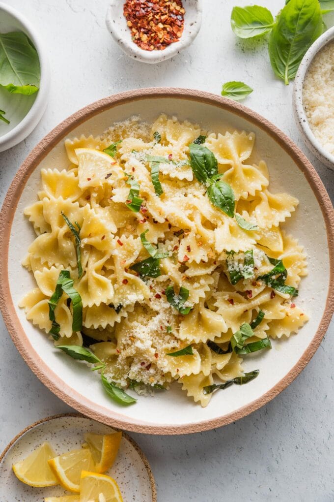Serving of lemon basil pasta with generously dusted fresh Parmesan cheese and red pepper flakes.