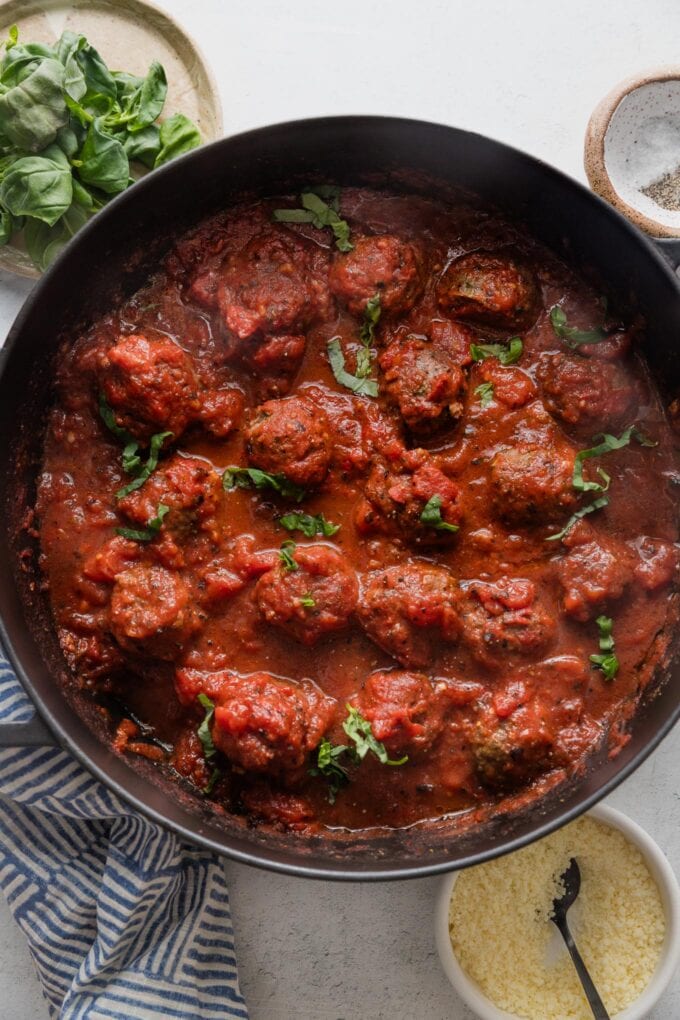 Large, deep-sided cast iron skillet full of homemade Italian meatballs simmering in a from-scratch marinara sauce.