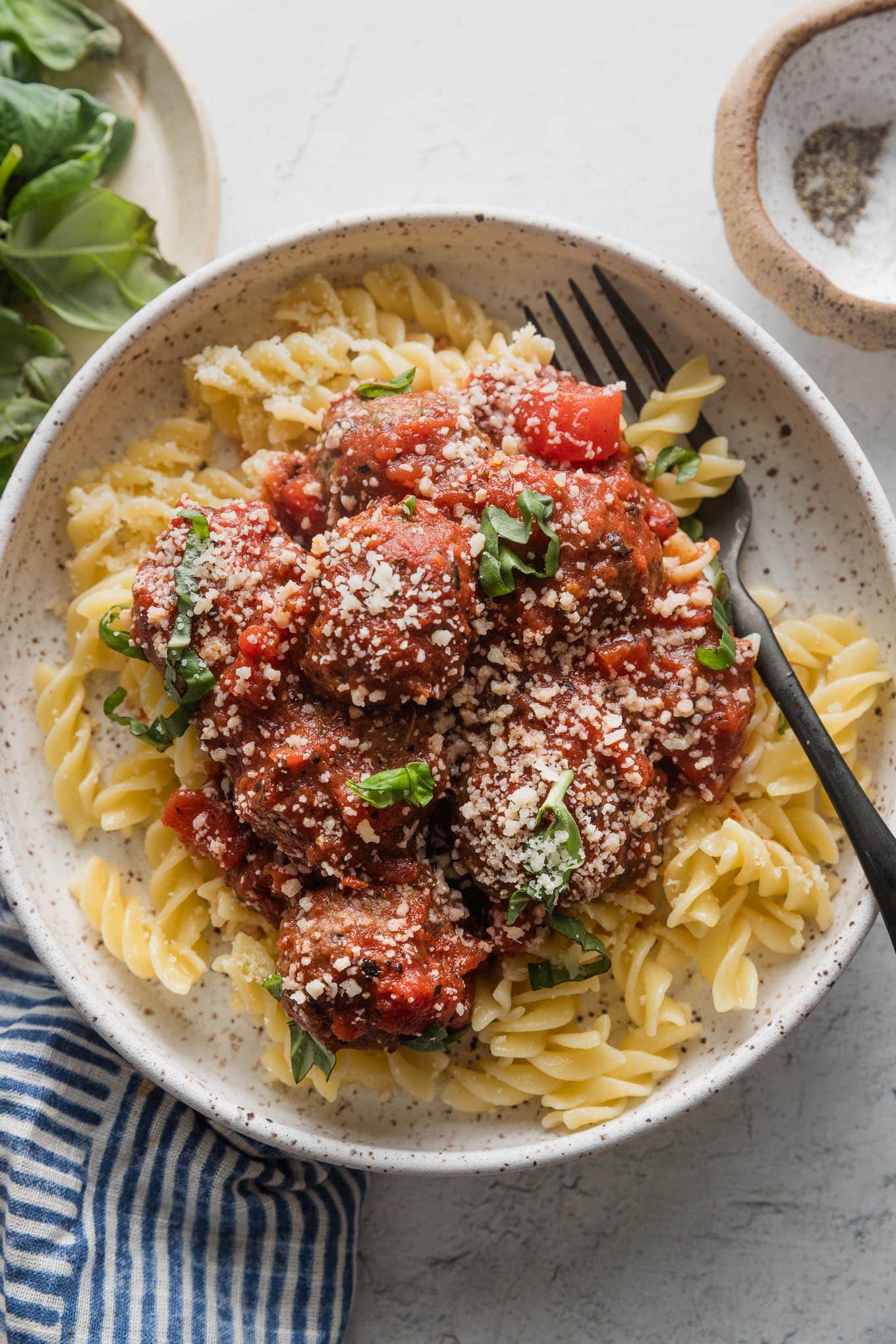 Close up of a small bowl filled with pasta and meatballs marinara.