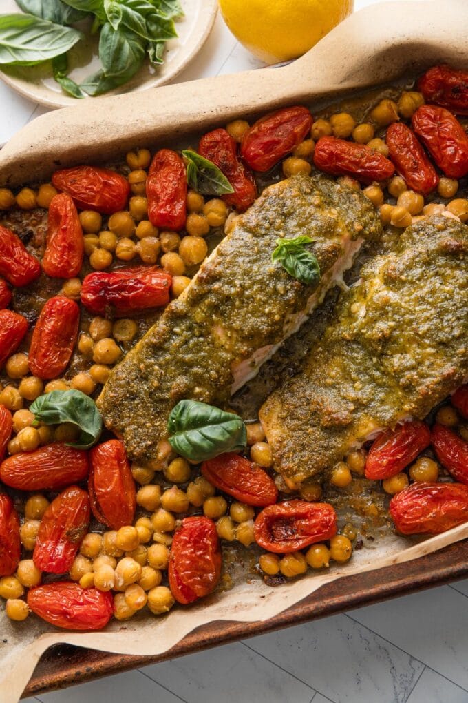 Sheet pan full of roasted pesto salmon, cherry tomatoes, and chickpeas, just pulled out of the oven and ready to eat.