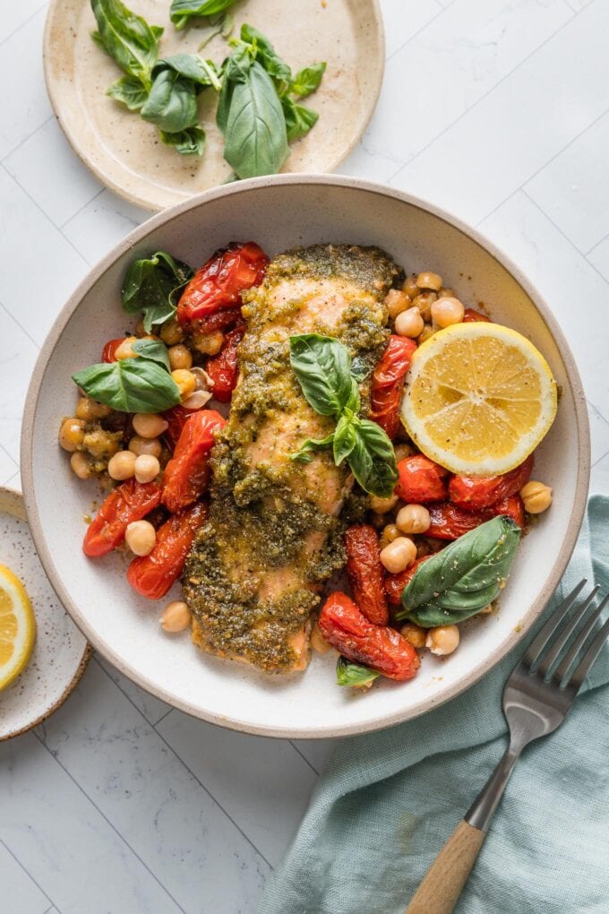 Salmon pesto bowl with roast cherry tomatoes and chickpeas, lemon juice, and fresh basil.