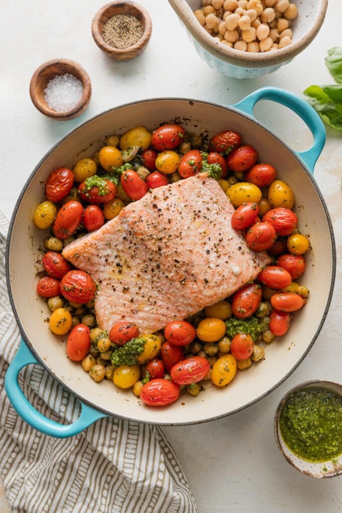 Pan with salmon, tomatoes, and chickpeas all roasted together with a spoonful of pesto.