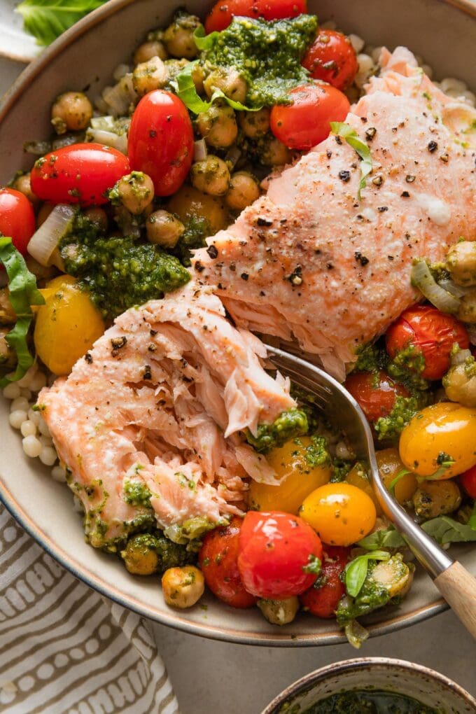 Close up of a fork flaking a piece of salmon.