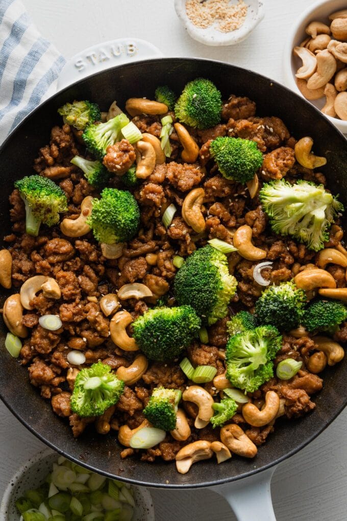 Cast iron skillet full of cashew chicken with broccoli and a quick homemade sauce.