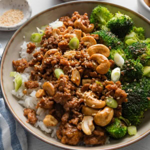 Bowl full of cashew chicken made with ground chicken and a quick homemade sauce, served over rice with broccoli and toasted sesame seeds.