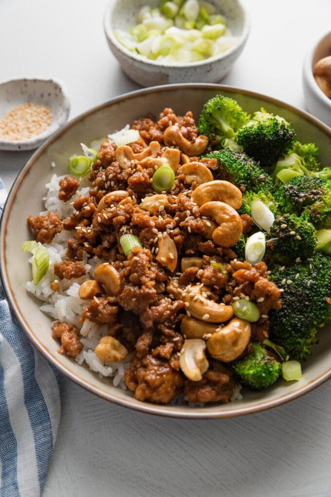 Bowl full of cashew chicken made with ground chicken and a quick homemade sauce, served over rice with broccoli and toasted sesame seeds.