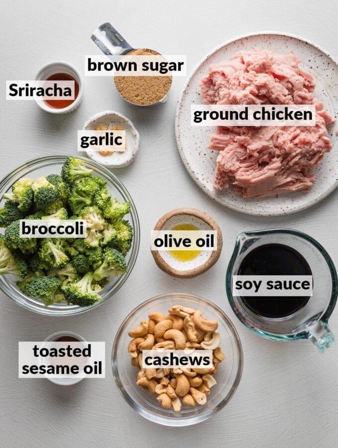 Labeled overhead photo of ground chicken, broccoli florets, cashews, olive oil, brown sugar, soy sauce, toasted sesame oil, garlic, and Sriracha, ready to cook.