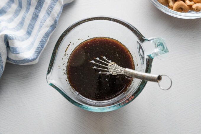 A quick, 4-ingredient sauce for cashew chicken whisked together in a small glass liquid measuring cup.