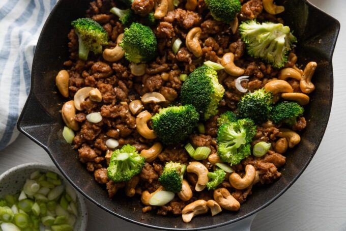 Broccoli added to skillet with ground chicken, cashews, and sauce.