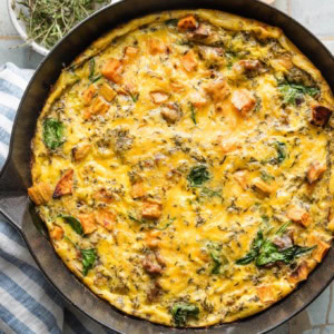 Close up overhead view of a sweet potato sausage frittata just removed from the oven, with cheese and spinach baked in.
