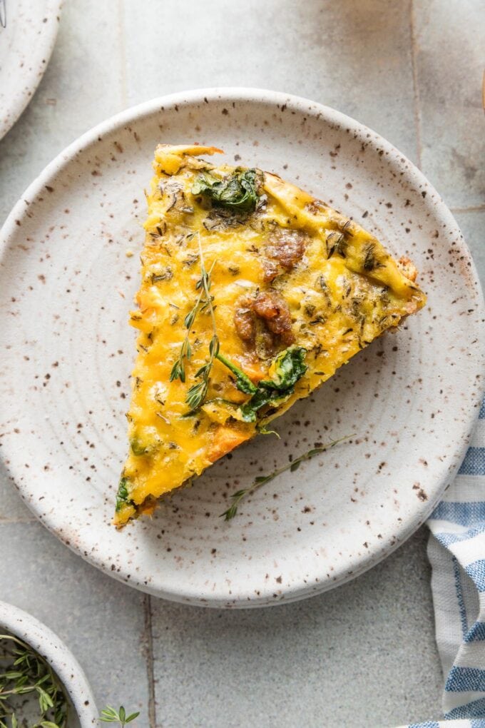 Close up view of a frittata slice with big chunks of sweet potato and sausage showing on top.
