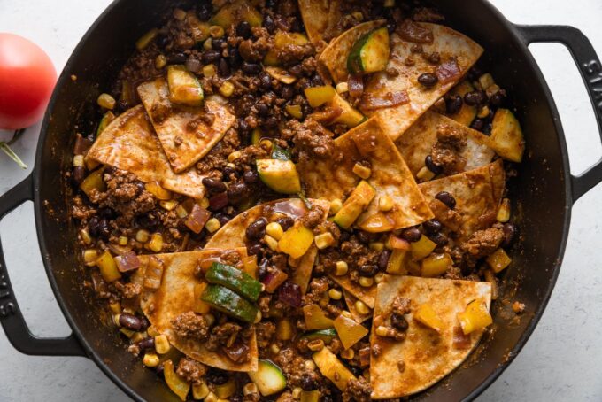 Tortilla wedges stuck into an enchilada skillet and ready to bake.
