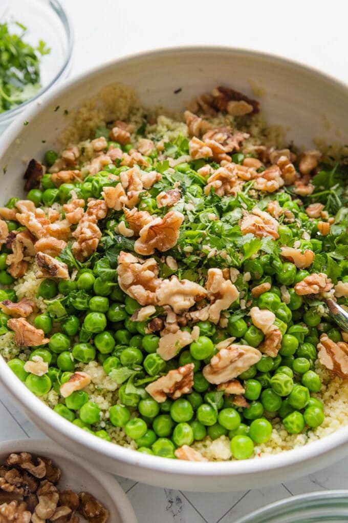 Walnuts and fresh parsley added on top of a couscous salad, but not yet mixed in.