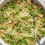 Bowl filled with a light, freshly-made couscous salad with peas, walnuts, and a homemade basil vinaigrette dressing.