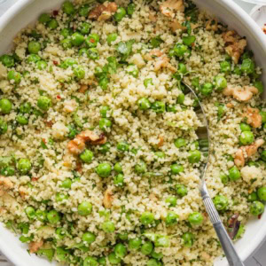Bowl filled with a light, freshly-made couscous salad with peas, walnuts, and a homemade basil vinaigrette dressing.