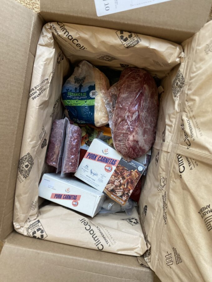 Overhead view of a ButcherBox, just arrived and opened to show products inside.