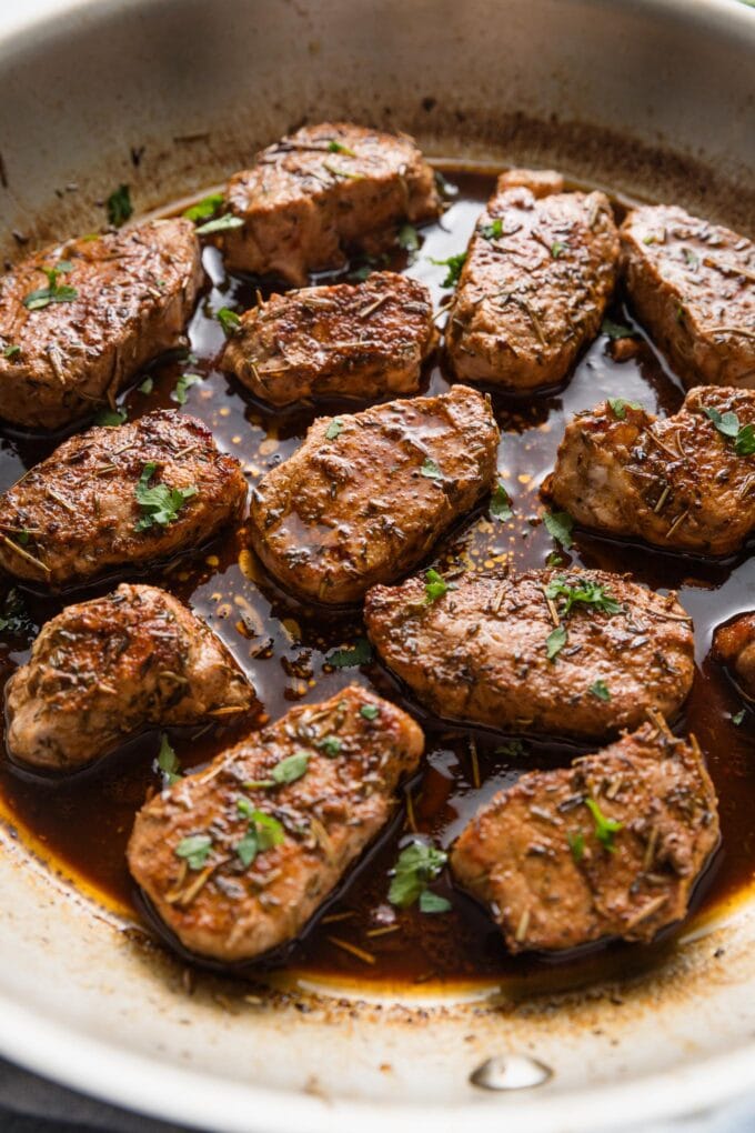 Skillet filled with pork medallions seared with a balsamic sauce.