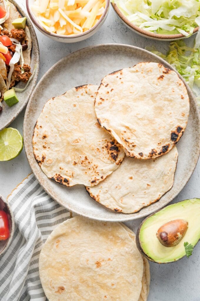 Soft flour tortillas lightly charred over a gas flame to blacken and brown them in spots.