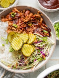 Easy and flavorful, these pulled BBQ chicken bowls make a flexible, build-your-own dinner that can please everyone. Tender, slow-cooked BBQ chicken, healthy homemade slaw, green onions, and crisp pickles are an irresistible combination!