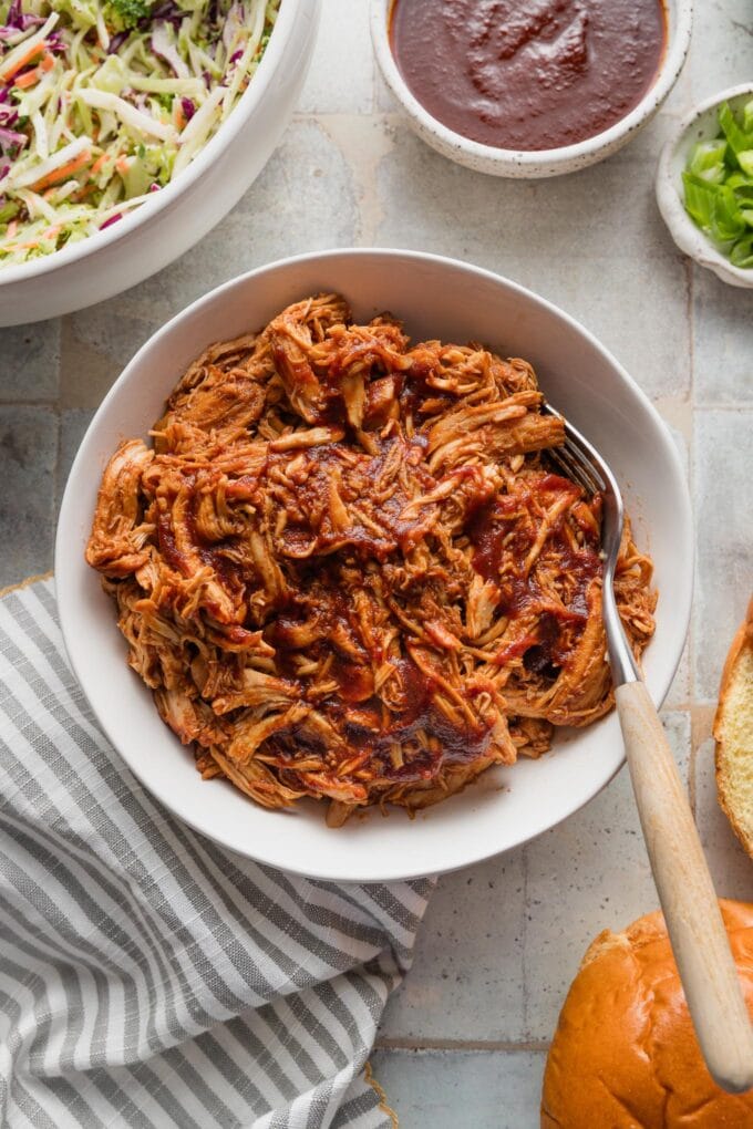 Bowl full of shredded BBQ chicken resting on a countertop.