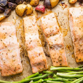Sheet pan with salmon filets, roasted asparagus, and herb-seasoned baby potatoes.