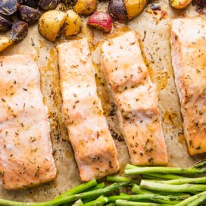 Sheet pan with salmon filets, roasted asparagus, and herb-seasoned baby potatoes.