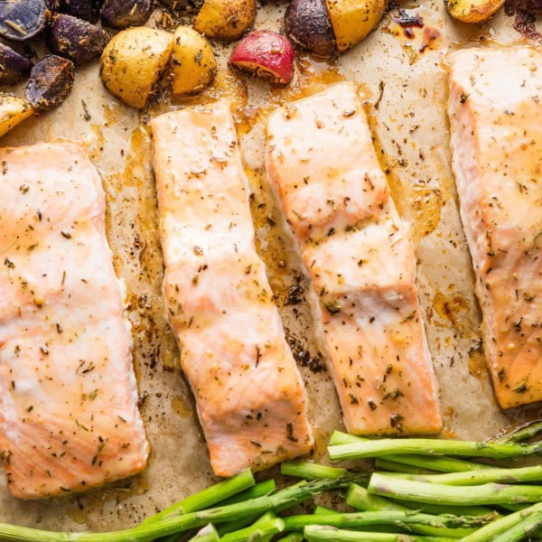 Sheet pan with salmon filets, roasted asparagus, and herb-seasoned baby potatoes.