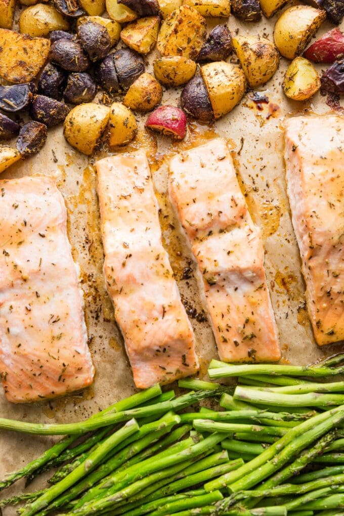 Sheet pan with salmon filets, roasted asparagus, and herb-seasoned baby potatoes.