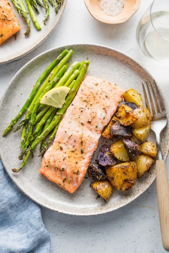 Small dinner plate filled with a roasted salmon filet, baby potatoes, and asparagus.