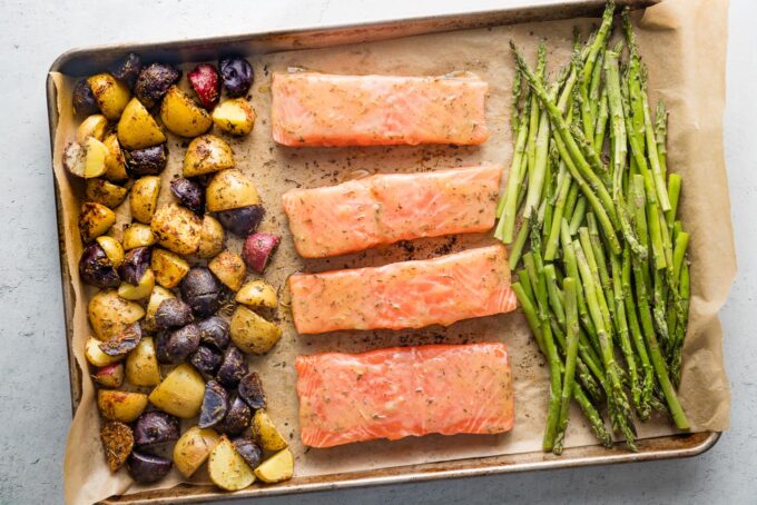 Glazed salmon and asparagus added to a sheet pan with partially-roasted baby potatoes.