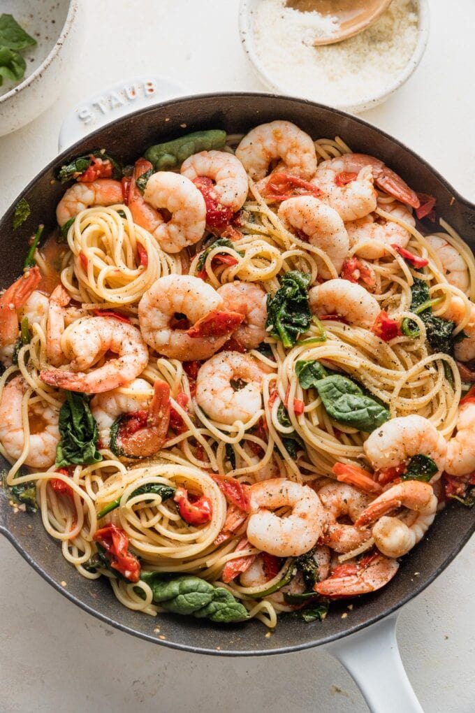 Cast iron skillet filled with a tomato spinach shrimp pasta ready to serve.