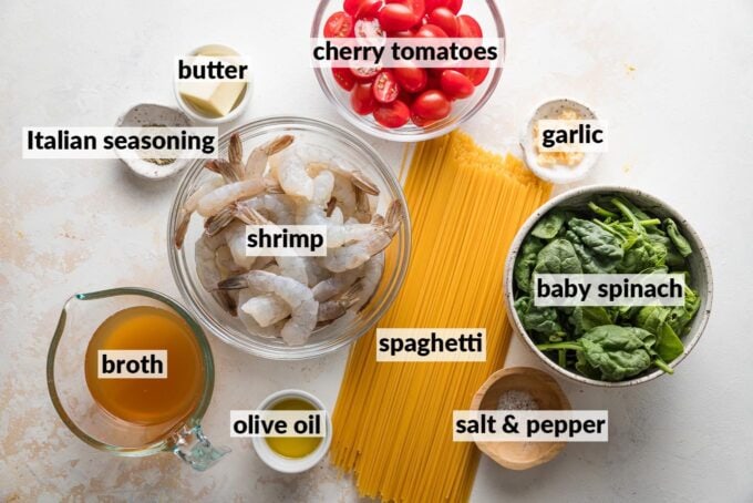Labeled overhead photo of dried spaghetti, raw shrimp, cherry tomatoes, baby spinach, butter, olive oil, broth, garlic, and Italian seasoning, all measured out and ready to cook.