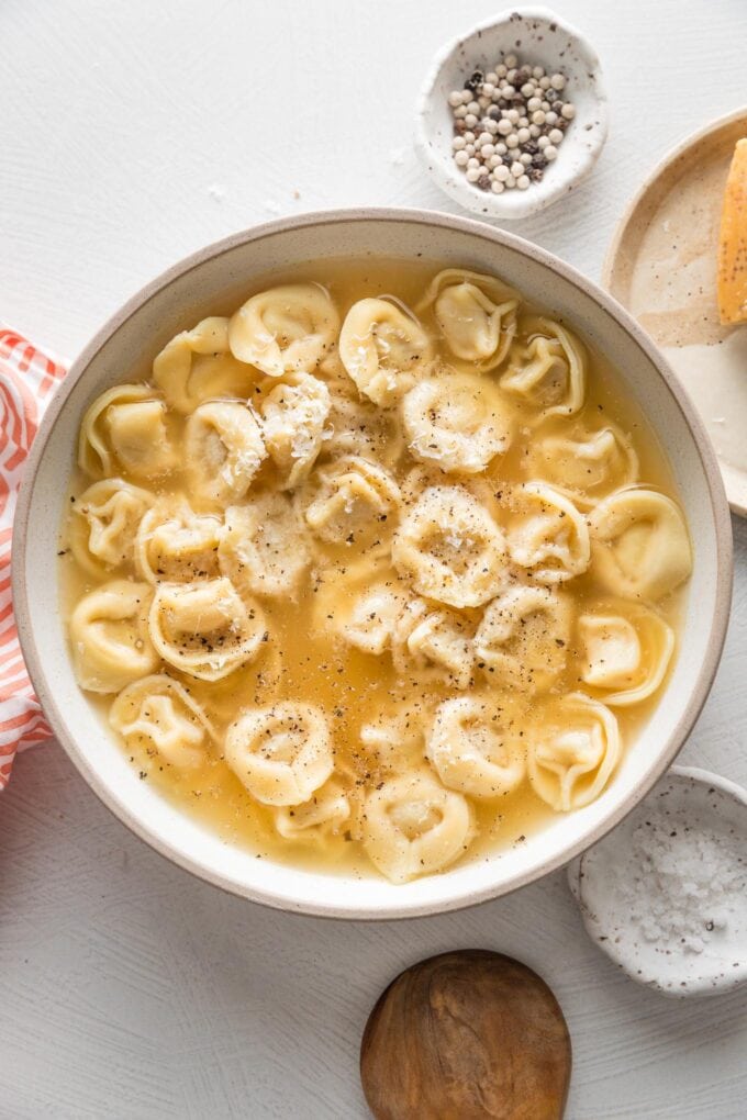 Countertop set with a bowl of tortellini warmed in bone broth, black pepper, and Parmesan cheese.