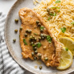 Small plate with a helping of buttered orzo and quick chicken piccata with extra lemon and capers.