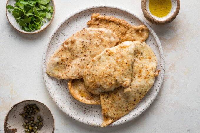 Pan-fried chicken breasts resting on a plate.