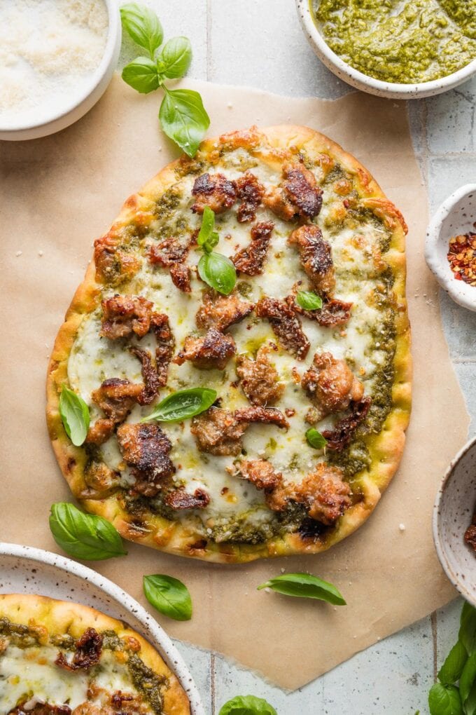 Flatbread pizza made with pesto, crumbled sausage, mozzarella, Parmesan, and sun-dried tomatoes.