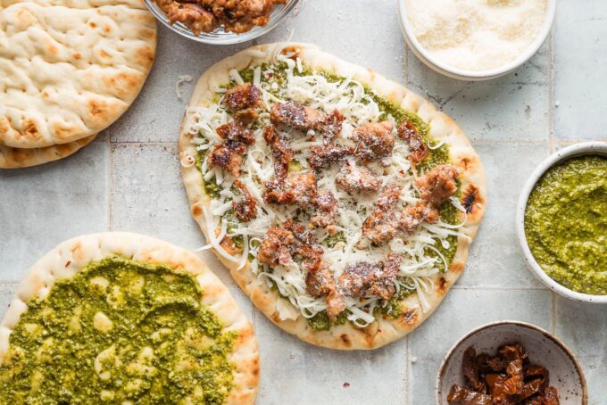 Naan flatbread pizza topped with sausage crumbles over pesto and mozzarella cheese.