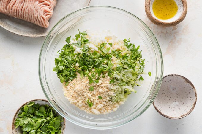 Overhead photo of a glass prep bowl full of Panko, shredded zucchini, feta, and seasonings.