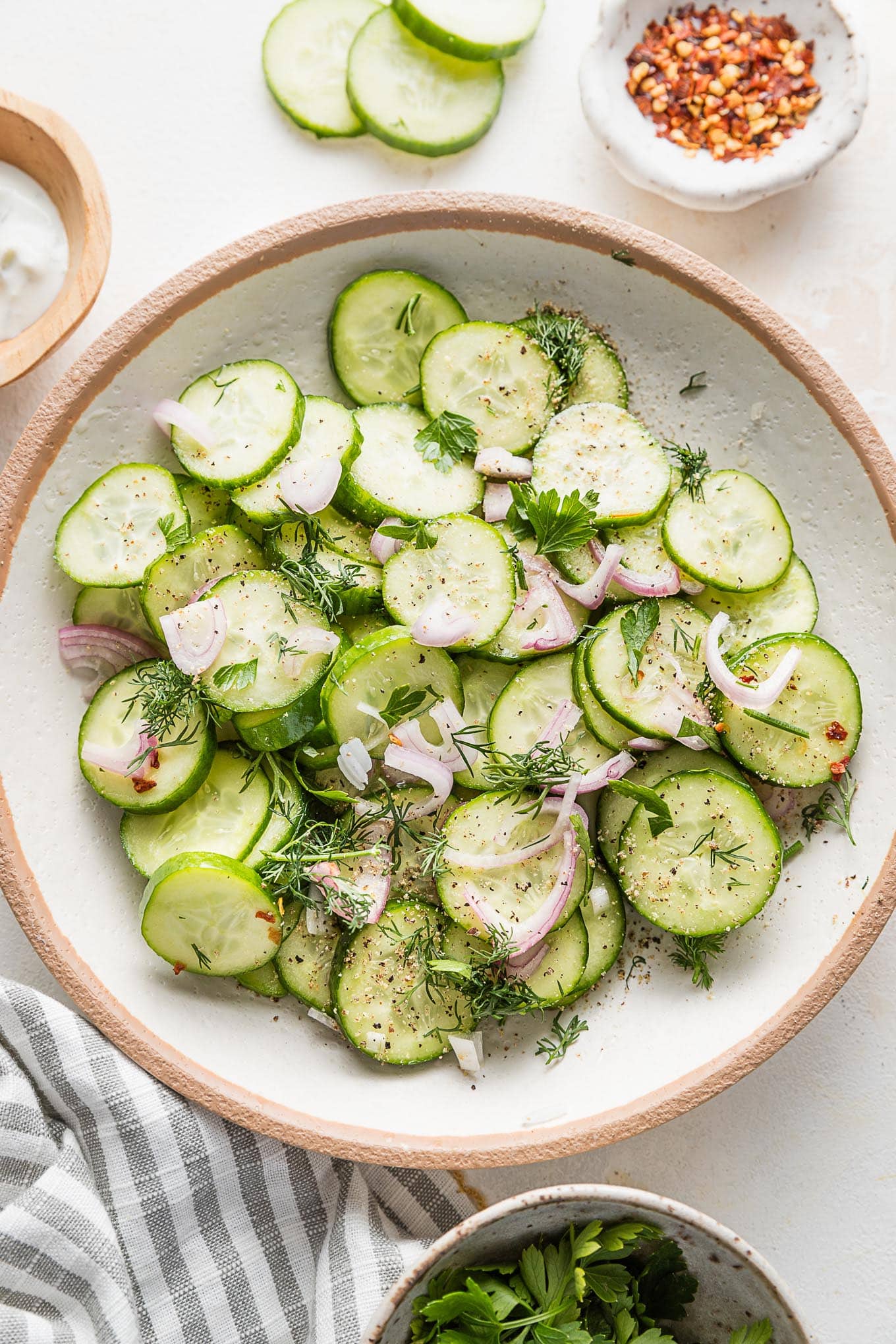 Small bowl full of a cucumber shallot salad with fresh dill and a light white wine vinegar and honey based marinade.