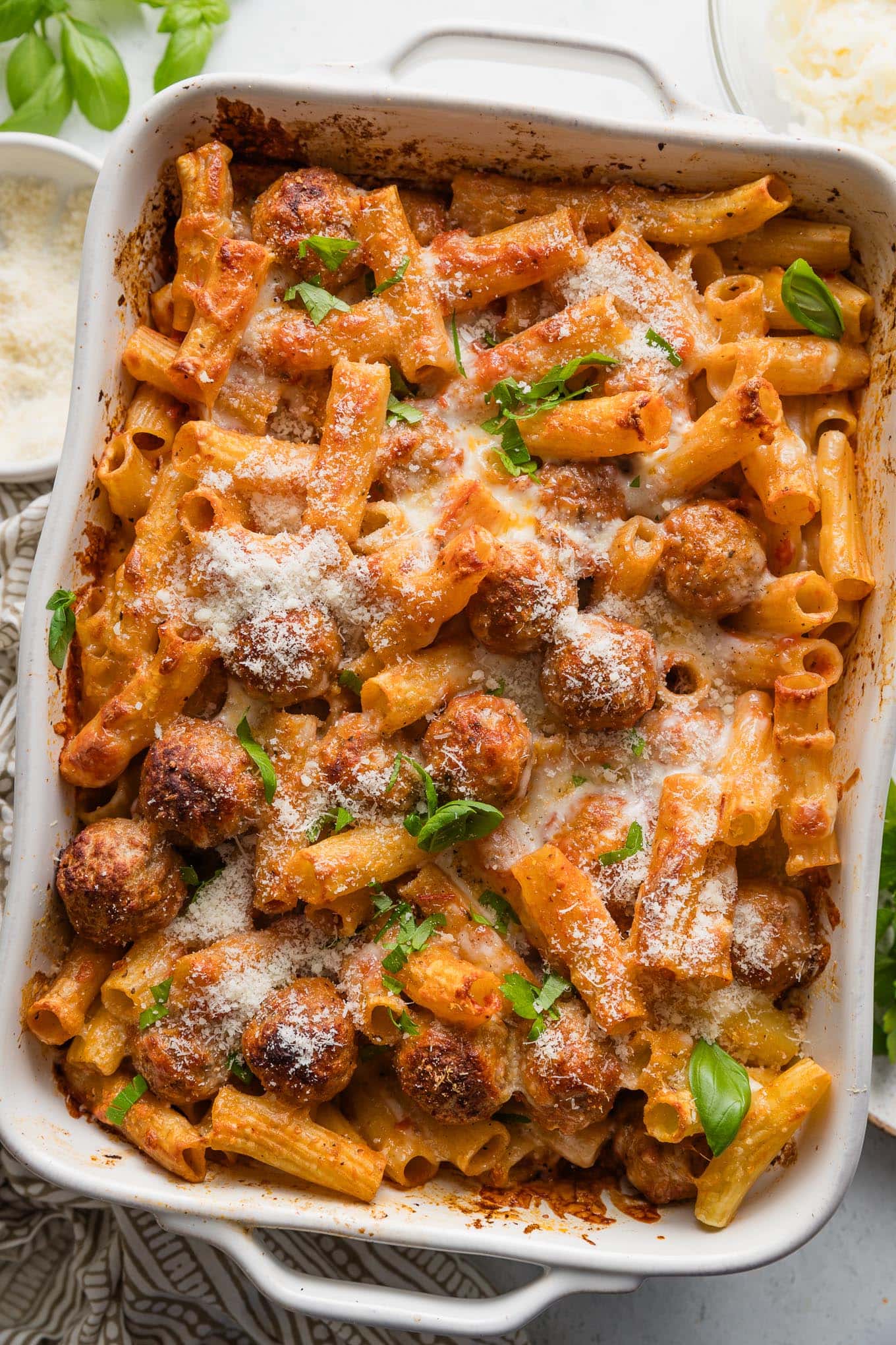 Large casserole dish full of baked rigatoni and meatballs.