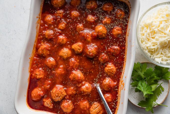 Meatballs stirred into a souped-up marinara sauce in a casserole dish.