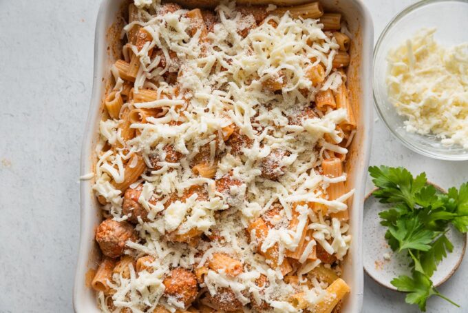 Rigatoni meatball bake with cheese sprinkled on top, ready to transfer into the oven.