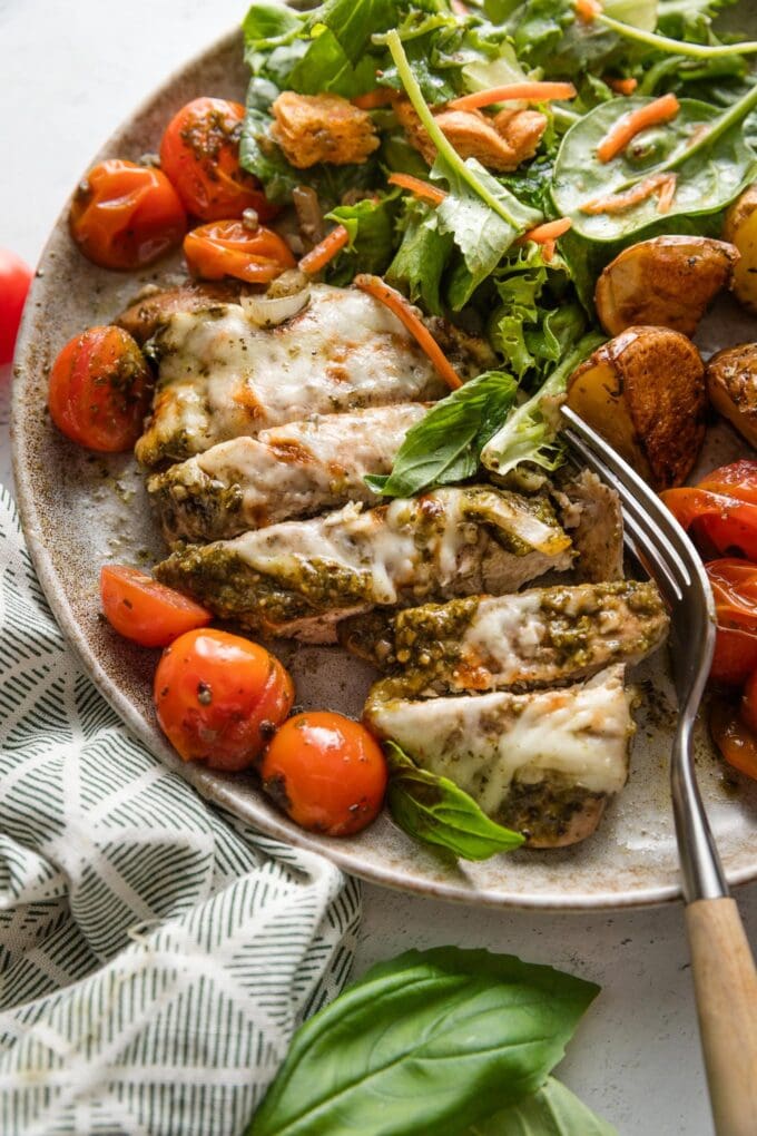 Sliced chicken breast smothered with basil pesto and mozzarella cheese, roasted and served with burst cherry tomatoes and shallots.