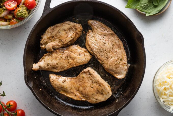 Chicken breasts seared in a cast iron skillet.