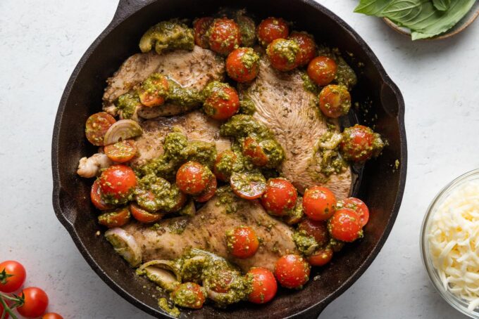 Pesto, tomatoes, and shallot added around seared chicken breasts.