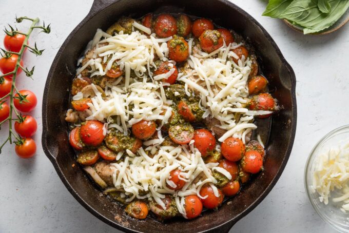 Mozzarella sprinkled over pieces of pesto-baked chicken.