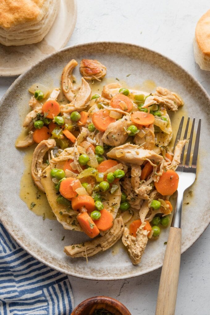 Overhead view of a plate of chicken and biscuits in a from-scratch sauce with carrots, peas, celery, and onions.